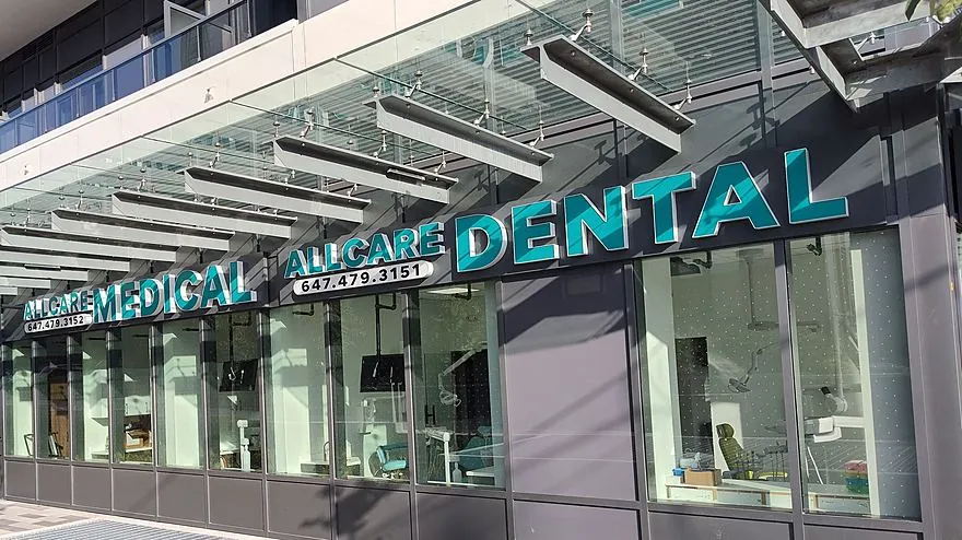 The glazed ground floor of 5105 Hurontario Street under its glass canopy, with the All Care Dental sign